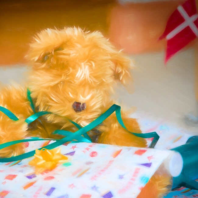 Billedet viser en bamse i gavepapir og et fødselsdagsflag.